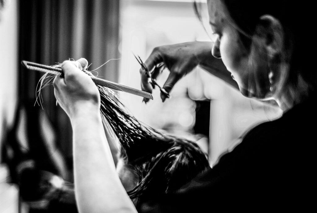 a woman cutting another woman's hair with a pair of scissors